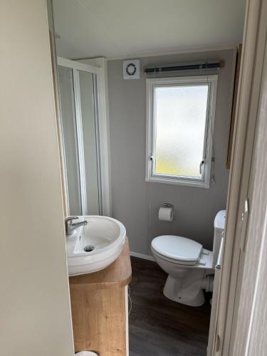 a bathroom with a sink and a toilet and a window at Glenlea in Selsey