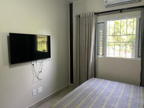 a bedroom with a bed and a flat screen tv on the wall at Villaggio dos Pássaros in Paranoá
