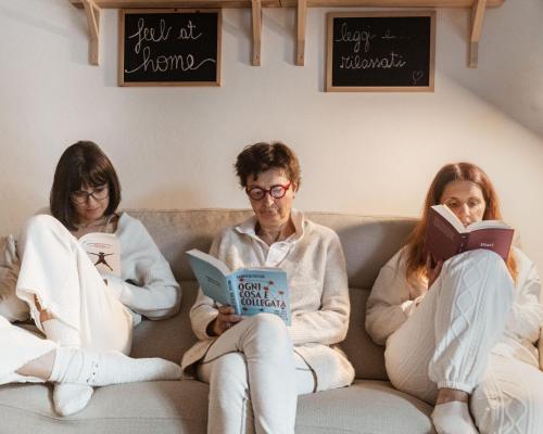 a group of people sitting on a couch reading books at Amy B&B casetta di charme in Vercelli