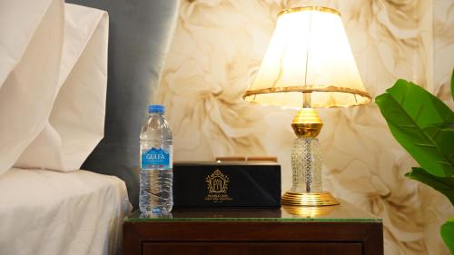 a bottle of water and a lamp on a table next to a bed at Service Apartment by World Inn in Karachi