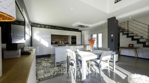 une cuisine et une salle à manger avec une table et des chaises blanches dans l'établissement GWENN HA DU Maison proche plage et GR34, à Concarneau