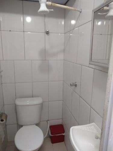 a white bathroom with a toilet and a sink at Quarto e Cozinha em Mongaguá in Mongaguá