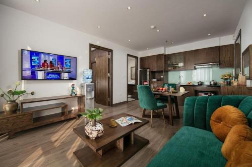 a living room with a green couch and a kitchen at Bloom in Hanoi - The Residences in Hanoi