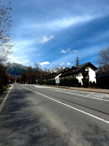 an empty road with houses and mountains in the background at Penzion Raimund in Smokovce