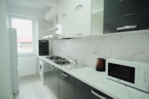 a white kitchen with a sink and a microwave at JAY House Radauti in Rădăuţi