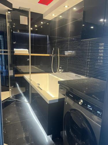 a bathroom with a tub and a washing machine at Apartament Stare Miasto Rynek Sienny in Szczecin