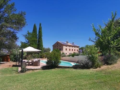 a backyard with a swimming pool and a house at Villa Giulia, a splendid farmhouse in the Marche region in Appignano
