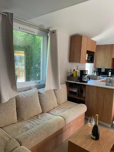 un salon avec un canapé et une cuisine dans l'établissement mobil home neuf du samedi au samedi, à Lège-Cap-Ferret