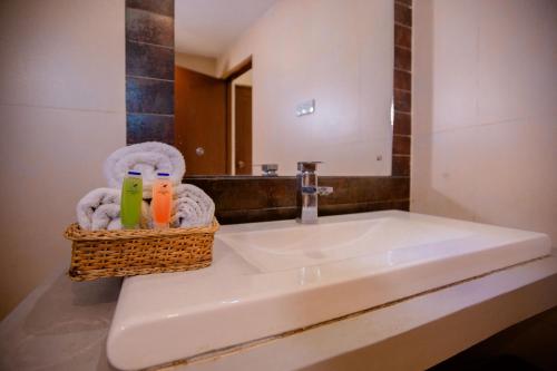 a bathroom sink with a basket of towels and a mirror at Lake Wind Resort in Tissamaharama