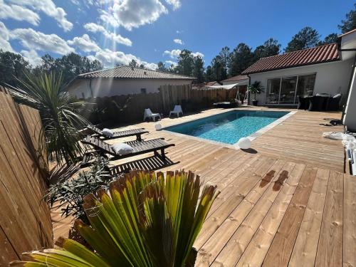 une cour arrière avec une piscine et une terrasse en bois dans l'établissement Villa Zerua & Spa, à Mimizan