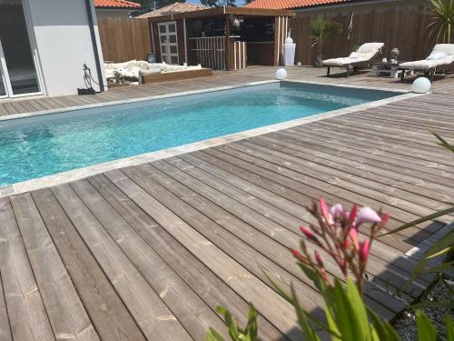 une piscine avec une terrasse en bois à côté d'une maison dans l'établissement Villa Zerua & Spa, à Mimizan