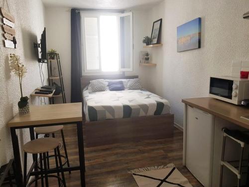 Cette petite chambre comprend un lit, un bureau et une cuisine. dans l'établissement Charmant studio à proximité du Vieux-Port, à Marseille