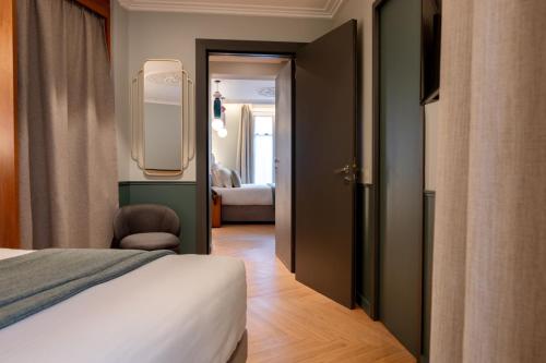 a bedroom with a bed and a mirror and a room at Grand Hotel Saint Michel in Paris