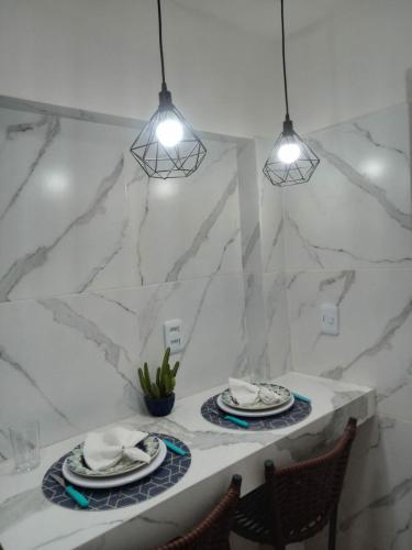 a dining room table with two plates and two lights at Kitnet de luxo perto do shopping da ilha in São Luís