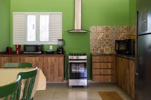 a kitchen with green walls and a stove and a table at Villaggio dos Pássaros in Paranoá