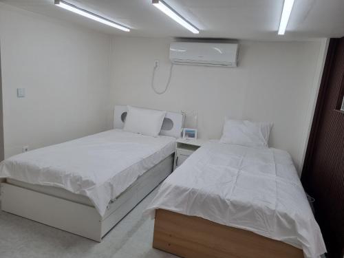 two beds in a room with white walls at Shin-Nonhyeon Hideout in Seoul