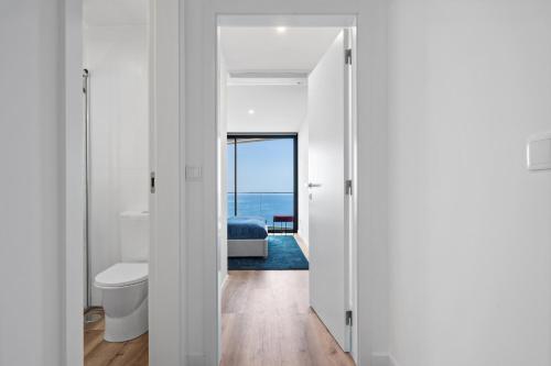 カマラ・デ・ロボスにあるOceanfront Elegance Madeira Retreatのベッドがあり海が見える寝室