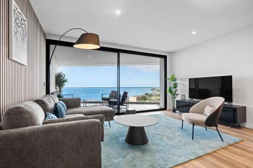 a living room with a couch and a table at Oceanfront Elegance Madeira Retreat in Câmara de Lobos