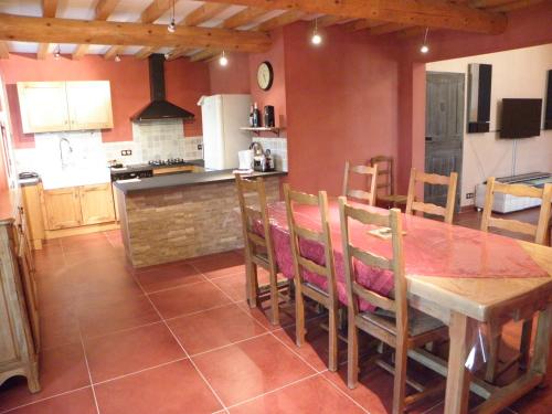 une cuisine et une salle à manger avec une table et des chaises en bois dans l'établissement Les bananiers, à Sauveterre
