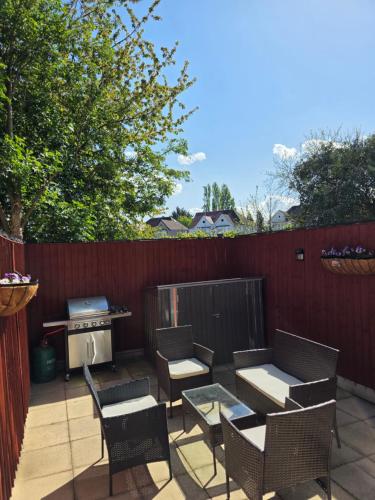 a patio with chairs and tables and a grill at Cozy flat & Lovely garden, High Speed WiFi in Cranford