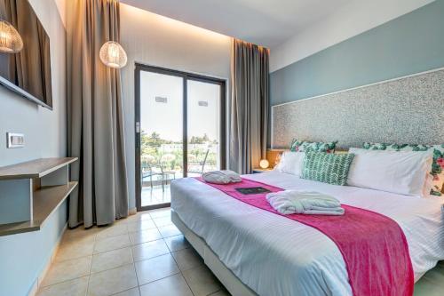 a bedroom with a large bed with a large window at Lindos Breeze Beach Hotel in Kiotari