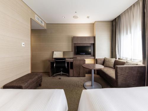 a hotel room with a couch and a desk at Nishitetsu Inn Kurosaki in Kitakyushu