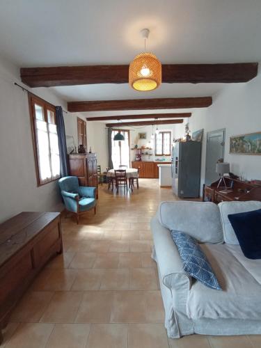 Una sala de estar con un sofá azul y una cocina. en La maison de Jules, en Saint-Guilhem-le-Désert