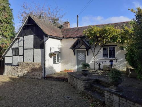 ein weißes Cottage mit einer Steinmauer in der Unterkunft Cosy 1 Bedroom Cottage, The Old Thatch, Bredon in Bredon