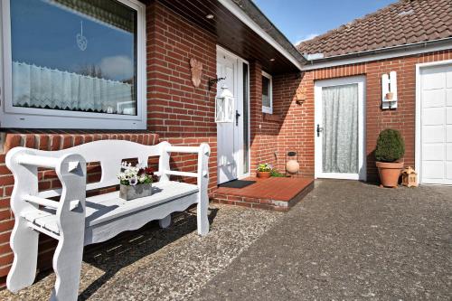 a white bench sitting outside of a house at Ferienwohnung Martina in Leck