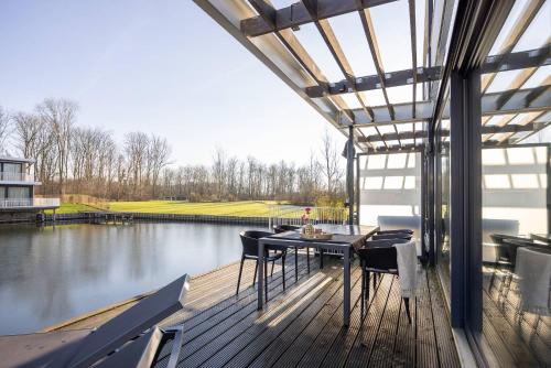 a deck with a table and chairs next to a pond at Hello Zeeland - Water Villa's Veerse Wende - with dog in Arnemuiden