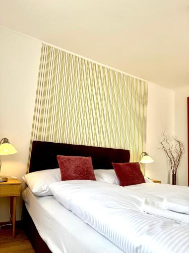 a bedroom with a large white bed with red pillows at Penzion Raimund in Smokovce