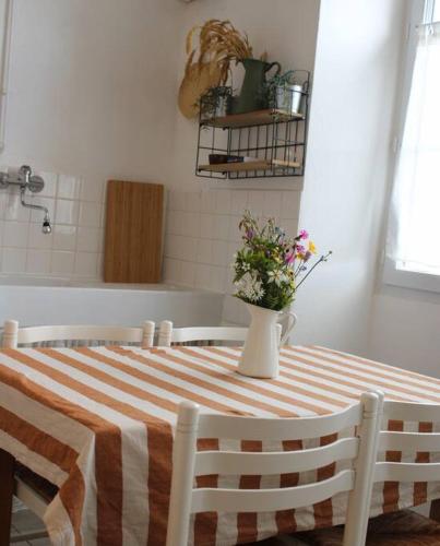 une table avec un vase de fleurs dessus dans l'établissement Picherande - Le Ravelou, appartement au coeur du Sancy, à Picherande