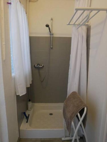 La salle de bains est pourvue d'une douche, d'une baignoire et d'une chaise. dans l'établissement Picherande - Le Ravelou, appartement au coeur du Sancy, à Picherande