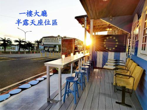 a table and chairs on a porch with a street at 燈塔情人海景民宿 in Eluan