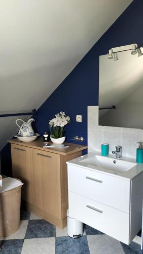 La salle de bains est pourvue d'un lavabo blanc et d'un mur bleu. dans l'établissement Appartement Vallée de la Risle, à Glos-sur-Risle