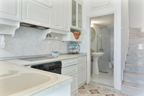a white kitchen with a sink and a tub at Olympos Blue in Olympos
