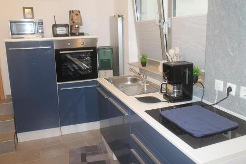 a small kitchen with a sink and a stove at Leocata-Sangiorgio in Neckartailfingen