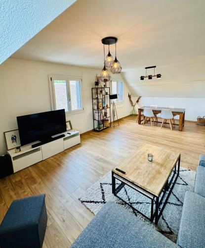 un salon avec une télévision et une table dans l'établissement Le Molay, à Beaune