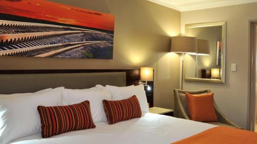 a hotel room with a bed and a painting on the wall at Cresta Mahalapye Hotel in Mahalapye