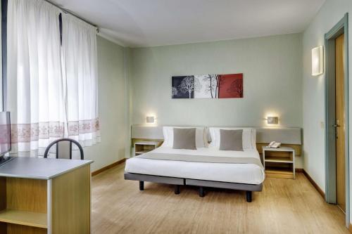 une chambre avec un lit, un bureau et une fenêtre dans l'établissement Best Western Hotel Residence Italia, à Quartu SantʼElena