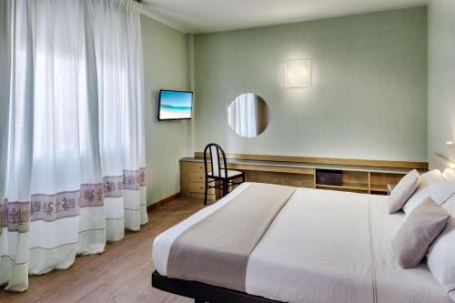 a bedroom with a bed and a chair and a mirror at Best Western Hotel Residence Italia in Quartu SantʼElena