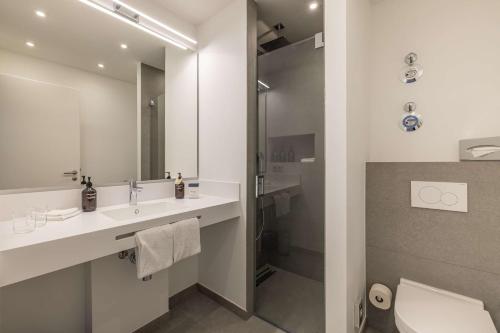 a bathroom with a sink and a toilet and a mirror at ATLANTIC Grand Hotel Travemünde in Travemünde
