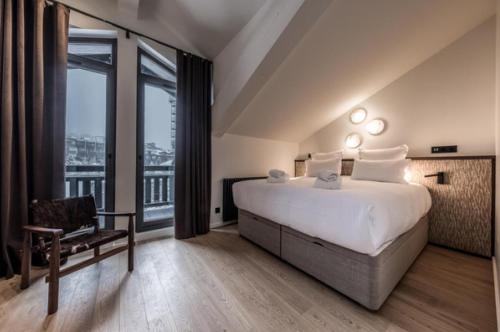 une chambre avec un grand lit et une grande fenêtre dans l'établissement JAMES TACC28 - exquisite apartment in the heart of Courchevel 1850, à Courchevel
