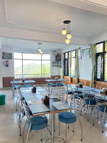 a dining room with tables and chairs and windows at Dolia Pahadi Myar Maiti in Rānīkhet