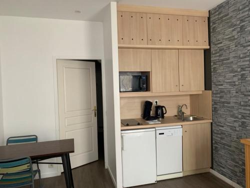 a kitchen with white cabinets and a table and a door at Studio dans une residence hoteliere avec piscine couverte in La Rochelle