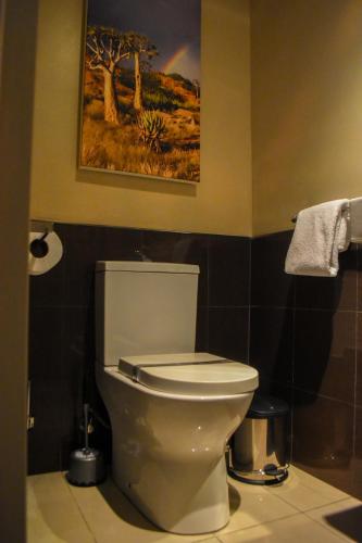 a bathroom with a toilet and a painting on the wall at Cresta Mahalapye Hotel in Mahalapye