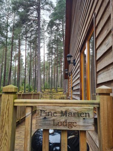 a wooden sign that reads pine marten lodge next to a building at Cairngorm Lodges in Aboyne