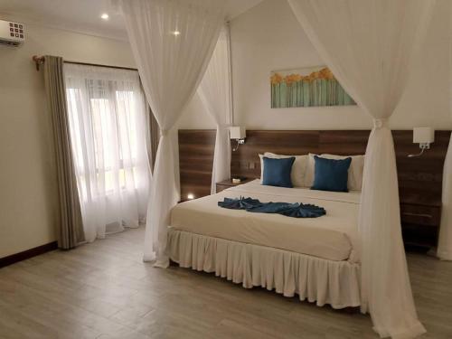 a bedroom with a large white bed with blue pillows at Lukenya Alkebu Resort in Nairobi