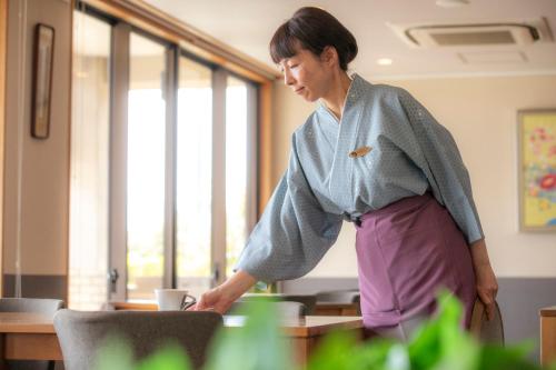 a woman standing in front of a table with a cup at Yuyaruru Saisai in Kanazawa