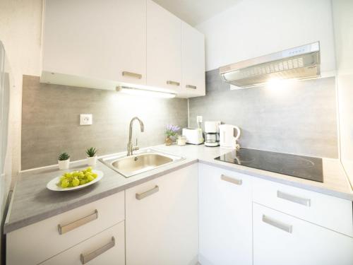 - une cuisine blanche avec un évier et un bol de fruits dans l'établissement Studio Ulysse Plage-4 by Interhome, à La Grande Motte